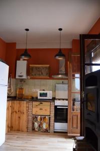- une cuisine aux murs orange et aux appareils blancs dans l'établissement Vivienda Rural El Peñón de Los Primillas, à La Iruela