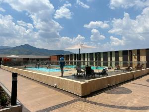 a man standing next to a swimming pool with an umbrella at Ubicación privilegiada. Todo al alcance de tu mano in Sabaneta