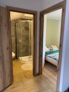 a bathroom with a shower and a bedroom with a bed at Apartamenty JENDRYCÓWKA in Korbielów