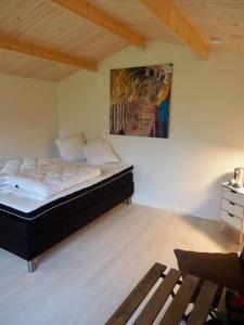 1 dormitorio con 1 cama y una pintura en la pared en Luksus i lønstrup, med kunsten i hovedfokus M en Lønstrup