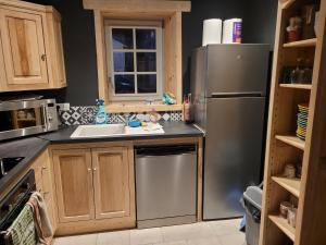 a kitchen with a stainless steel refrigerator and a sink at Les Forsythias in Messeix