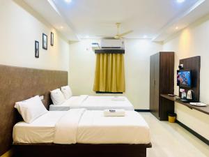 a hotel room with two beds and a television at Deccan Suites, Tirupati in Tirupati