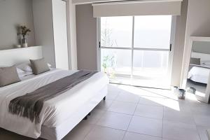 a white bedroom with a large bed and a large window at Charlie Suites en el casco histórico de Salta in Salta