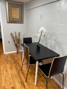 un tavolo nero con sedie e un vaso con dei fiori sopra di The Legato Suite a Brooklyn