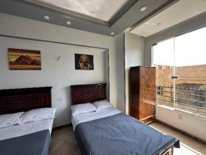 a bedroom with two beds and a large window at black pyramids view in Cairo