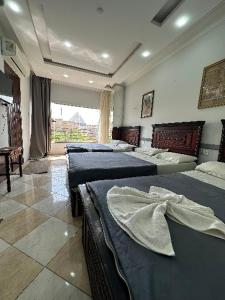a bedroom with three beds and a window at black pyramids view in Cairo