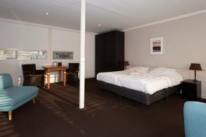 a bedroom with a bed and a chair and a table at Restaurant-Hotel de Watergeus in Noorden