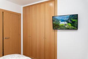 a television hanging on a wall in a bedroom at AndBnB I Refugio sobre el Río, Esquí y Parking gratis in Ransol