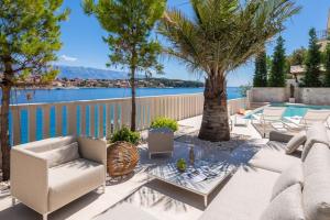 a patio with palm trees and a swimming pool at Luxury Villa Bohemian 2 heated pool near sea in Selca