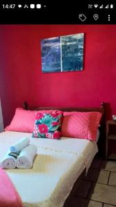 a bed with two towels and a red wall at Pousada paraíso no Mar in Matinhos