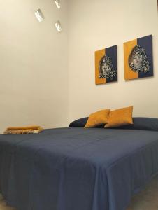 a bedroom with a blue bed with four pictures on the wall at Casa Basilico' Taormina in Taormina