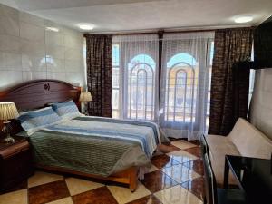a bedroom with a bed and a chair and windows at Bonita casa chica con amplio patio in Coatepec