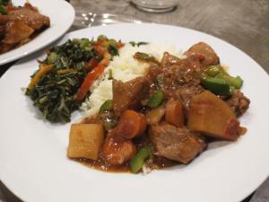 a plate of food with meat and vegetables on a table at Villa Luna in Port Antonio