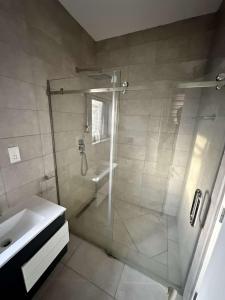 a bathroom with a glass shower and a sink at Pine Court in Accra