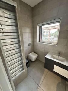 a bathroom with a sink and a toilet and a window at Pine Court in Accra