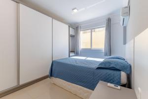 - une chambre avec un lit bleu et une fenêtre dans l'établissement Apartamento em Bombas - Ótimo para Famílias, à Bombinhas