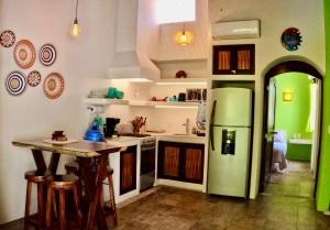 a kitchen with a green refrigerator and a table at Casa Kaz: Penthouse 1 Bedroom in Zihuatanejo