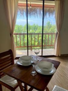 - une table en bois avec 2 assiettes et des verres à vin dans l'établissement Rustica House frente al lago - Ayampe, à Ayampe