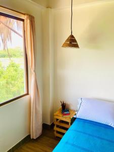 - une chambre avec un lit bleu et une fenêtre dans l'établissement Rustica House frente al lago - Ayampe, à Ayampe