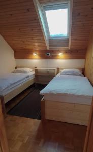 2 Betten in einem kleinen Zimmer mit Dachfenster in der Unterkunft Apartment Jezerka in Cerknica