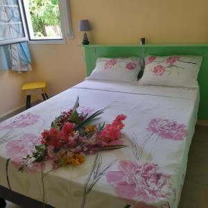 una camera da letto con un letto decorato con fiori di canelle a Le Diamant