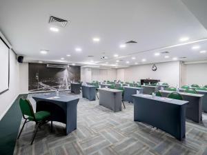 a conference room with chairs and tables and a screen at Hotel M Privilege Moema São Paulo in Sao Paulo