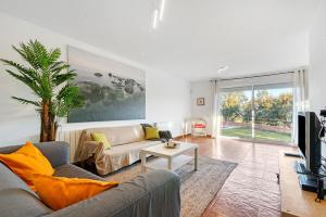 uma sala de estar com um sofá e uma televisão em Casa Roure-4BR-Piscina-BBQ-Vistas Mar-Ping-Pong em Sant Cebrià de Vallalta