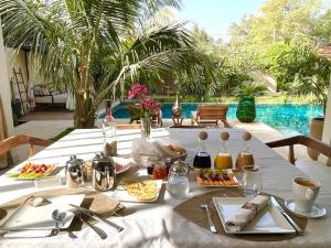 Ngaparou的住宿－Villa YEMAYA - Villa d'hôtes，一张带食物的白色桌子和游泳池