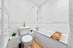 uma casa de banho branca com um WC e uma banheira em Kensington Station Proximity 2-Bedroom Apartment, Walk to Station in 2 Minutes em Londres