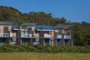 a building on the beach with trees in the background at Cosy Corner Sea View Apartments in Albany