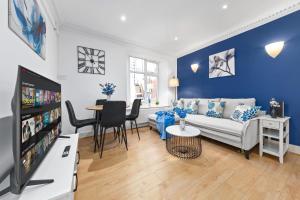 a living room with a couch and a tv at Kensington Station Proximity 2-Bedroom Apartment, Walk to Station in 2 Minutes in London