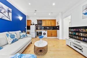 uma sala de estar com um sofá e uma mesa em Kensington Station Proximity 2-Bedroom Apartment, Walk to Station in 2 Minutes em Londres