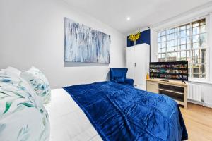 um quarto com uma cama azul e uma cadeira azul em Kensington Station Proximity 2-Bedroom Apartment, Walk to Station in 2 Minutes em Londres