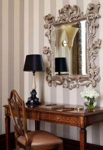 uno specchio e una scrivania con lampada e sedia di Anantara Palazzo Naiadi Rome Hotel - A Leading Hotel of the World a Roma