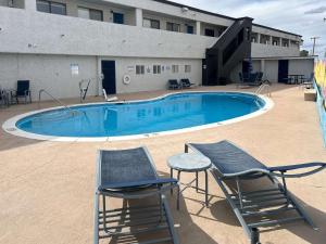 a swimming pool with two chairs and a building at Studio 6 Sierra Vista, AZ Fort Huachuca in Sierra Vista