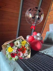 a bouquet of flowers and a balloon on a bed at Chalé no Litoral 01 in Torres