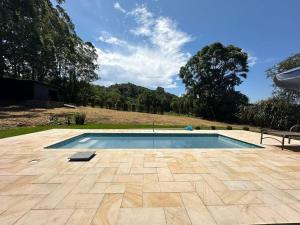 a swimming pool in a yard with a bench at Refúgio Romântico com Jacuzzi na Natureza a 10 min da Praia in Torres