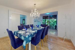 een eetkamer met een tafel met blauwe stoelen en een kroonluchter bij Villas Tropical 11 in Cancun