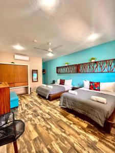 2 łóżka w pokoju z niebieskimi ścianami i drewnianą podłogą w obiekcie Bahia Tolok w mieście Isla Mujeres