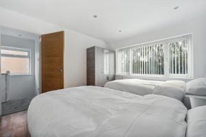 a white bedroom with two beds and a window at house in Heald Green village in Manchester