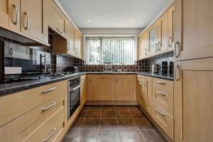 a large kitchen with wooden cabinets and stainless steel appliances at house in Heald Green village in Manchester