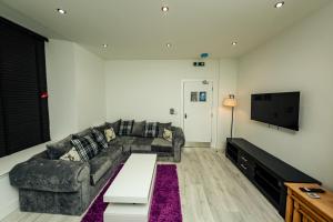 a living room with a couch and a tv at CHEERZ Apartments in Aberdeen