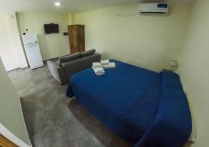 1 dormitorio con 1 cama azul y 1 sofá en Altos la Villa en San Rafael
