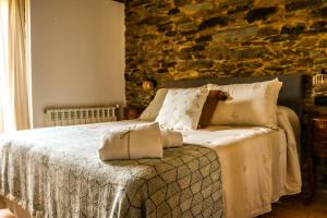 Schlafzimmer mit einem Bett mit weißer Bettwäsche und Kissen in der Unterkunft Fogar de Lecer in Arzúa