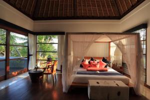 a bedroom with a canopy bed with red pillows at Villa The Jiwa in Tanjung +23 photos