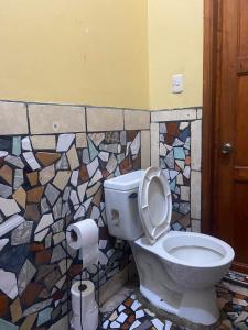 a bathroom with a toilet and a mosaic wall at El Jardín de Banu in Magdalena Milpas Altas