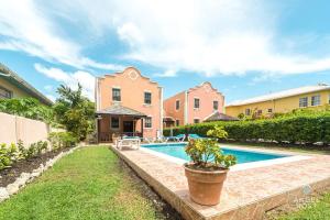 a villa with a swimming pool in front of a house at 2-Story Townhome with Private Pool, Ideal for Group! in Christ Church