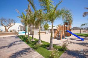 une aire de jeux avec des palmiers et un toboggan bleu dans l'établissement New Townhome with Private Patio, Parking & Pool Onsite, à La Paz