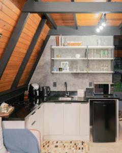 a kitchen with white cabinets and a black refrigerator at Chalé no Litoral 01 in Torres