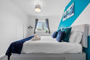 a bed with blue and white pillows and a window at Monthly Rates Cosy 3 Bed Free Parking -Contractors Families in Solihull